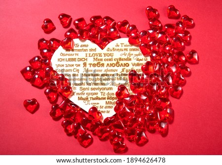 candy in the shape of hearts on a red background. the inscription "I love you" in different languages of the world