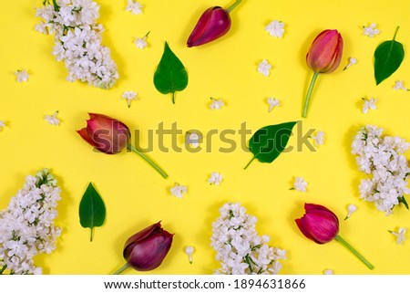 Red tulips, white lilac and green leaves on a yellow background. View from above. Blank for a postcard. Mother's Day, Valentine's Day, Birthday celebration concept. Spring. Top view, greeting card.