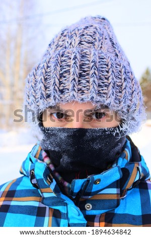 Frozen face of a girl covered with frost. The girl is wearing a hat and a mask