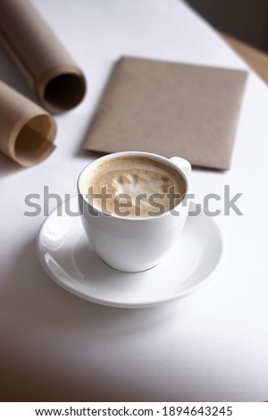 Fresh Coffee with Milk Froth Served on White with Beige Kraft Paper. Home Office Design.
