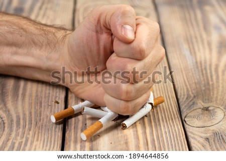 Do not smoke. Close-up of a male hand breaking a cigarette with a fist. Quit smoking.