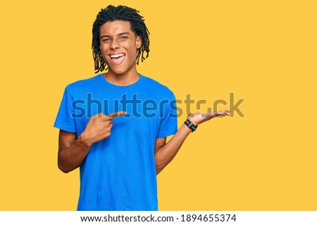 Young african american man wearing casual clothes amazed and smiling to the camera while presenting with hand and pointing with finger. 
