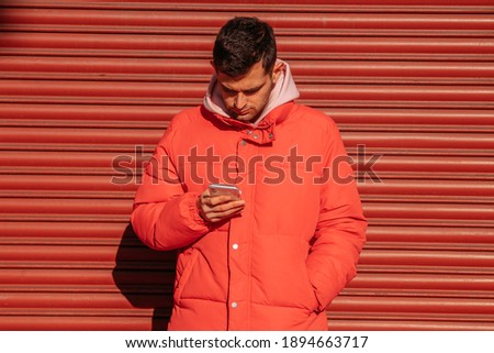 young man with mobile phone on the street red blind