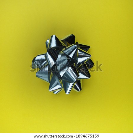 Silver bows on yellow background. Holiday concept.