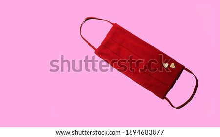 protective medical mask, fabric, red color, with a pair of wooden hearts, on a pink background, Protection against viruses, bacteria