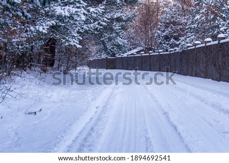 falling snow and road near the fence