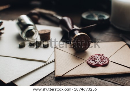 Letter seal with wax seal stamp on the wood table. Vintage notary stamp and sealed envelope. Post concept. Sealing wax. Wax seal. Dark academia style. Scandinavian hygge styled composition. Royalty-Free Stock Photo #1894693255