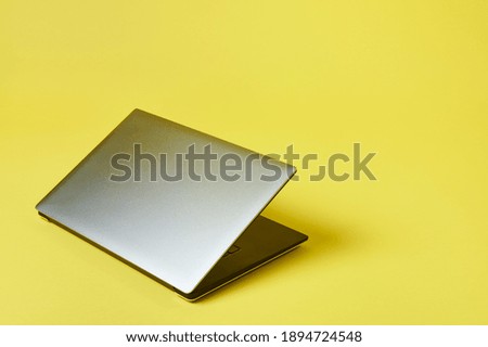 Grey laptop isolated on a yallow background. Top view with copy space, flay lay.