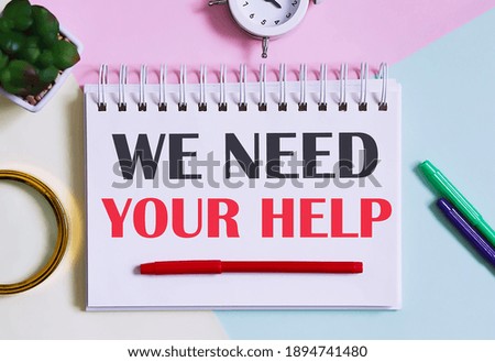 WE NEED YOUR HELP text written on notebook with pencils, magnifier