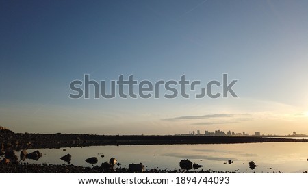 
wonderful view of the city of boston seen from across the bay,blue sky at the orange background and the sea in the middle