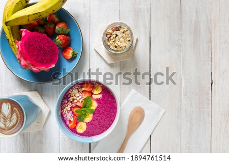 A fresh smoothie bowl made from banana, dragon fruit, milk and strawberries served in a bowl for a healthy nutritious breakfast - Tabletop food and lifestyle flat-lay image