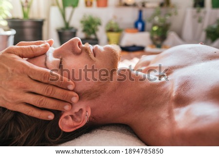 Stock photo of man enjoying face massage while lying in a towel.