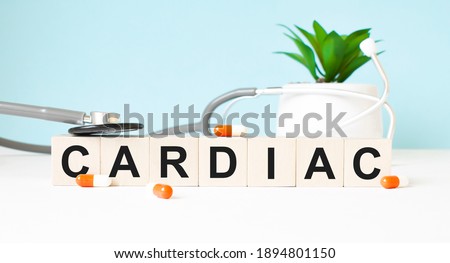 The word CARDIAC is written on wooden cubes near a stethoscope on a wooden background. Medical concept
