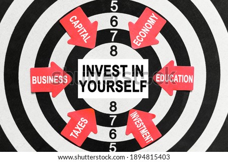 Business and finance concept. On the target, arrows with business lettering point to the center on a business card with the inscription - INVEST IN YOURSELF