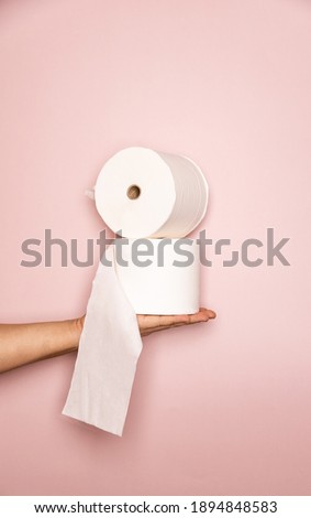 Holding 2 toilet rolls on the hand with a pink pastel background photoshoot suitable for ads and commercial for healthcare toiletries and cleanliness