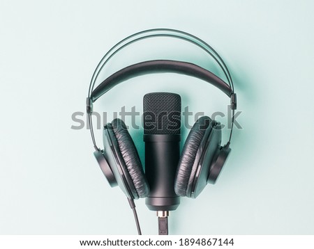 Modern headphones and microphone on a blue background. Equipment for recording and reproducing sound.