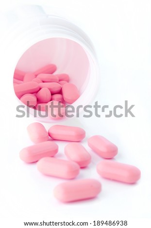 Closeup of pink pills and pill bottle