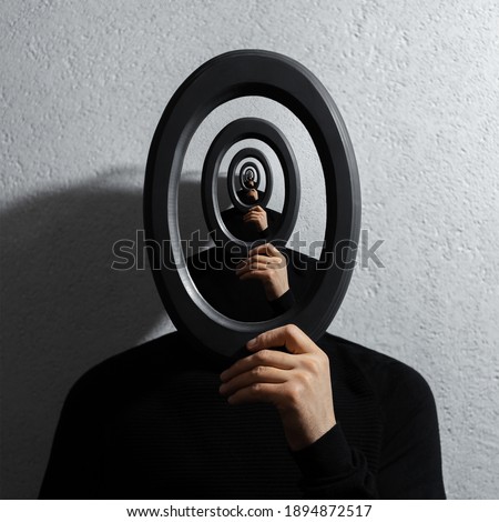 Enigmatic surrealistic optical illusion, young man holding round frame on textured grey background. Royalty-Free Stock Photo #1894872517