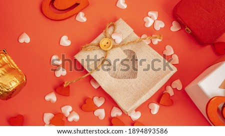 Top view on the table on Valentine's Day, March 8, Mother's Day. with a bottle of champagne, a box with a ring, a gift box with a red ribbon bow, hearts on a red background