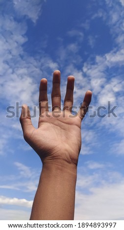 A hand arisen. Blue sky as background. Symbol of power and masculinity.