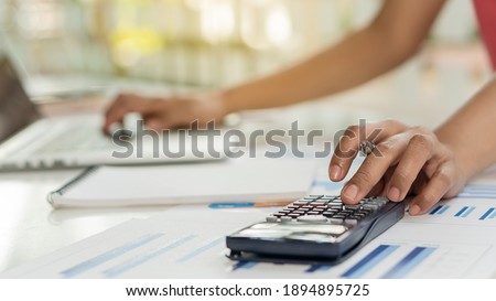 Young woman presses black calculator right hand to calculate while working in finance department in financial concept.