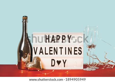 Happy Valentines day lightbox with golden heart and sparkling wine bottle. 14 February greeting card