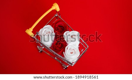Red and white roses flower on shopping cart on red background. Shopping holiday for valentines day love concept