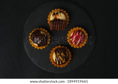 Flatlay picture of cheese tart been serve on slate plate and matte table on dark background.