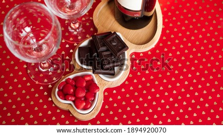 Chocolates and sweets on heart-shaped plates. Festive table setting for date of lovers. Red background