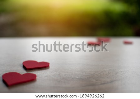 Concept valentine's day, a red heart symbol placed on a wooden table. Take a close-up and selective focus, copy space for design and text. Blurred background.