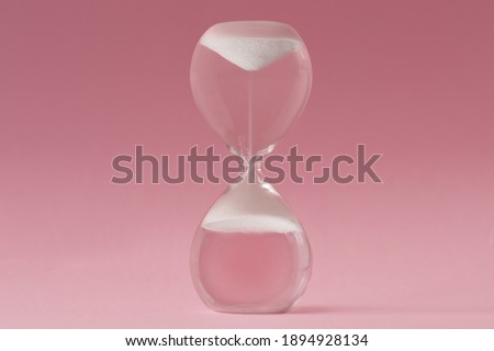 Upside-down hourglass on pink background - Concept of reverse time Royalty-Free Stock Photo #1894928134