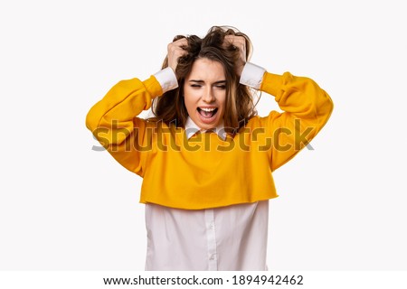 Portrait of woman in panic shouting and grabbing her head in fear or frustration. Stress and mental health. Studio shot, white background