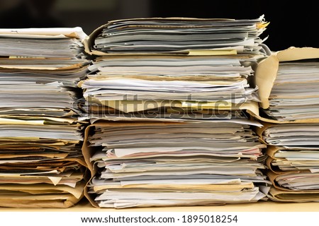 Close-up of piles of files in folders stacking up in a messy order. Royalty-Free Stock Photo #1895018254