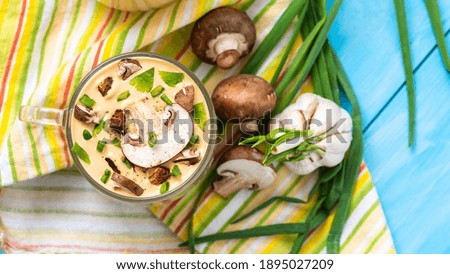 Traditional delicious mushroom soup with chopped mushrooms on a blue wooden background.