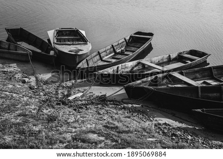 Wooden authentic old boats on the river bank. Life in the village of ordinary people. Transport and fishing vehicle. Black and white photo.