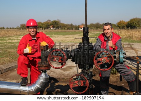 Oil Well and Two Oil Workers. Oil and Gas Industry. Oil worker and oil engineer giving thumb up sign. Teamwork.