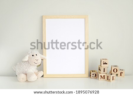 Wooden frame mock up for photo, print art, text or lettering, with nursery toys. Blank frame on white table.	