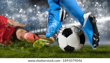 Football player man in action on dark arena background. Soccer player making sliding tackle Royalty-Free Stock Photo #1895079046