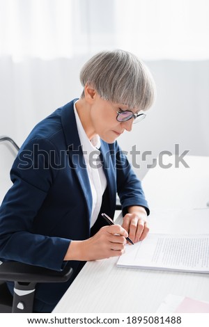 middle aged team leader signing document on desk