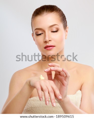 Young woman putting cream on her hand Isolated on white background