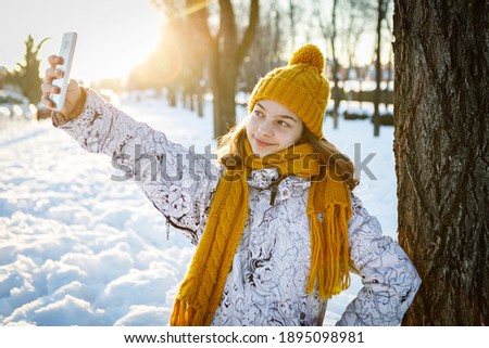 Young Girl Take Selfie With smart Phone Over snowy background