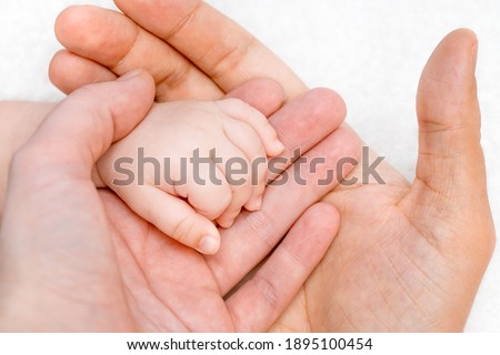 Parents hands holding new born baby hand. Love, care, peace concept.