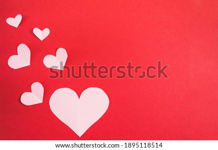 Paper hearts of different sizes on a red background. Abstract background with paper cut shapes. Sainte Valentine, mother's day. birthday greeting cards, invitations. Template for design. Copy space.