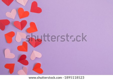 Valentine's Day background. Pink and red hearts on a pastel purple background. Valentine's Day concept. Layout for postcards and congratulations. Flat lay, top view, copy space