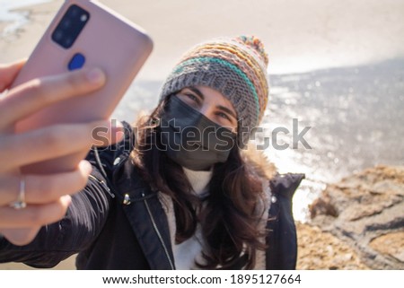 Beautiful girl next to the beach in winter make selfie with smartphone 