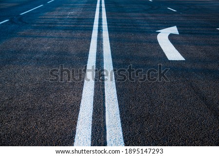 Road markings on asphalt on the street. White dividing line and special road marking symbols on black asphalt Royalty-Free Stock Photo #1895147293