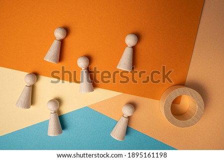 Figures and circular wooden piece of wood as people on multicolored papers

