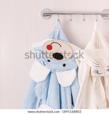 Blue and white baby bathrobes in bathroom. Close up. Embroidery on hood