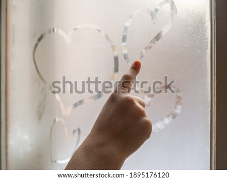 Finger draws hearts on the window.
