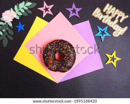 Happy birthday and donut on black background, stars